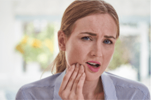 Mulher com dor na face em Alphaville, representando os sintomas de DTM e dor orofacial, buscando tratamento especializado e sem cirurgia.