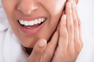 Mulher com dor na face em Alphaville, representando os sintomas de DTM e dor orofacial, buscando tratamento especializado e sem cirurgia